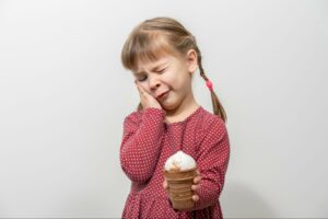 Enfant souffrant de douleurs dentaires tenant de la crème glacée